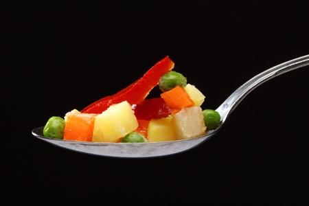 Frozen vegetables in a spoon over blackの写真素材
