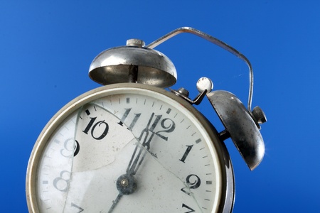 Close up of old broken alarm clock over blue