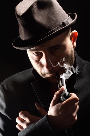 close portrait of a pipe smoker on a black backgroundの写真素材