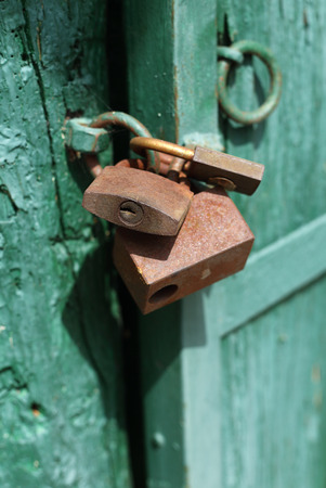 Old rusty padlocks on green door close up の写真素材