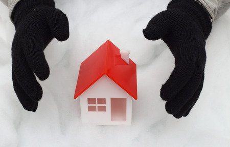 Model of house guarded by hands in winter glovesの写真素材