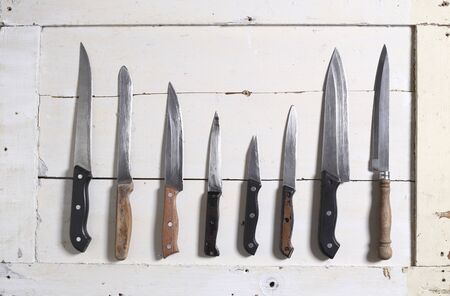 collection of various kitchen knives on white woodの写真素材
