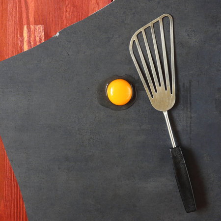a metal kitchen spatula and a raw eggの写真素材