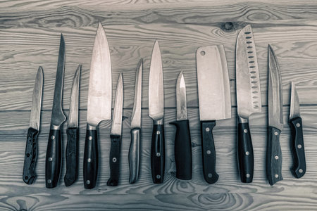 monochrome different kitchen knives on wooden tableの写真素材