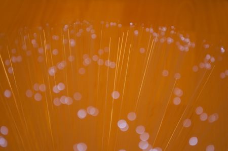 Close up capturing the ends of many fibre optic light strands giving a vibrant golden light. Focused only on a few central strands.の写真素材