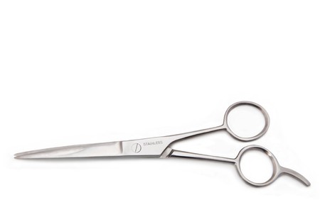Close up of a pair of stainless steel hairdressing scissors arranged over white.の写真素材