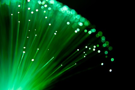 Close up abstract style capturing the ends of illuminated emerald colour fibre optic light strands arranged over black.の写真素材