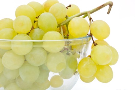 Close and low level angle capturing a glass bowl of grapes arranged over white.の写真素材
