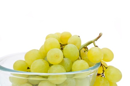 Close and low level capturing a glass bowl containing fresh green grapes arranged over white.の写真素材