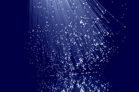 Close and low level capturing many illuminated blue fibre optic light strands against blue background.の写真素材