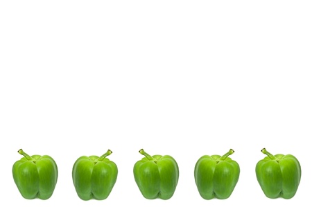 Five small whole green peppers arranged horizontally along the bottom border of the image over white.の写真素材