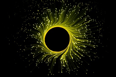 Many illuminated yellow fiber optic light strands in ring formation against black backgroundの写真素材