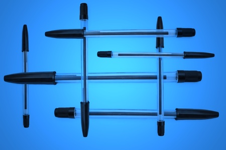 A selection of several black pens overlapping each other over blue light effectの写真素材