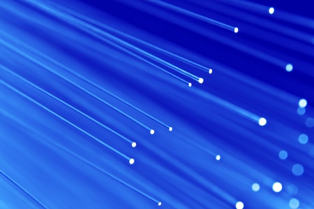 Close up on the ends of a selection of illuminated blue fiber optic light strands with blue background.の写真素材