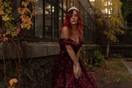 Beautiful girl in a long red dress with a crown on her headの写真素材
