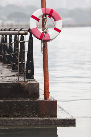 Life buoy hanging on a post at the pier by the riversideの写真素材