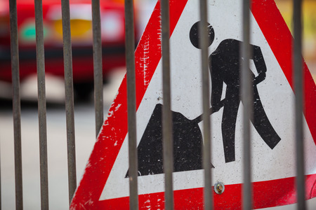 Sign of a construction site at a street behind a fence