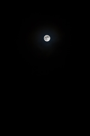 Illuminated moon at black night sky at a far away distanceの写真素材