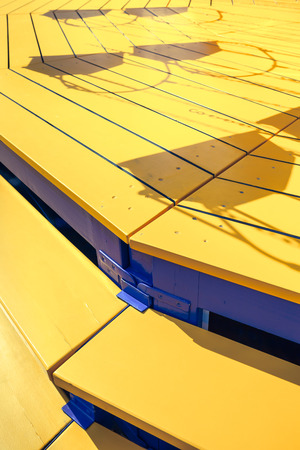 Detail of yellow wooden stairs of a swing carousel and shadows of the swing seats on the planksの写真素材