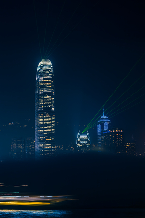 Illuminated city skyline detail of Hong Kong at night with foggy cloud in foreground and lights of...