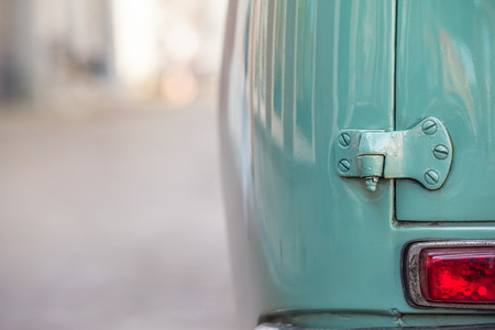 Closeup taillight and hinge of the rear door at mint green oldtimer car seen from back at street