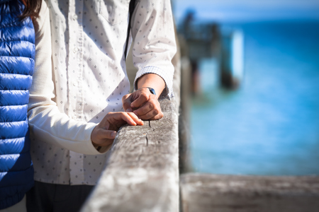 Hands of young couple near together at old pier railing by the seaの写真素材