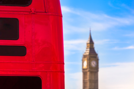 Back detail of red London bus with black windows and destination boards and Big Ben clock tower in...