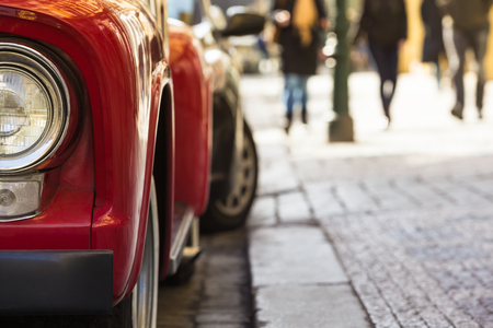 Closeup parking vintage red car and blurred legs of passersby at the sidewalk background (copy space)の写真素材