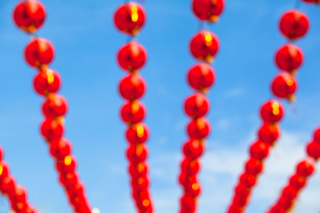 Blurred background of many rows red chinese paper lanterns in front of blue skyの写真素材