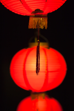 Close up of red chinese paper lanterns in a row up to down at dark nightの写真素材