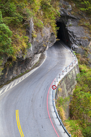 Serpentine mountain road leads to dark tunnel in Taiwan (copy space)の写真素材
