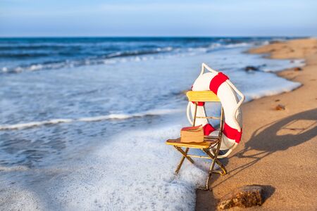 Vintage vacation scene miniature garden chair at beach shore wave, decorated by nostalgic life buoy...