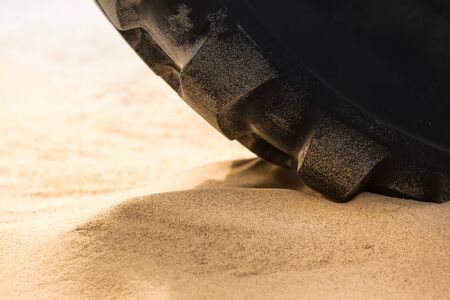 Close up huge heavy tire of tractor on soft ground like beach sand (copy space)の写真素材