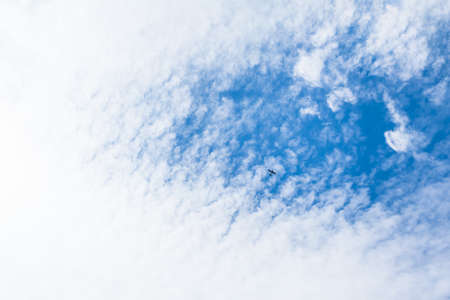 View up to opening of blue sky above white cloud cover, small aircraft crossing (copy space)の写真素材
