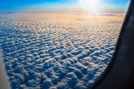 View from plane window to rising sun above blanket of clouds (copy space)
