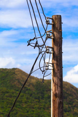 Old wooden pole of power transmission at rural area with cables and ceramic insulators (copy space)の写真素材