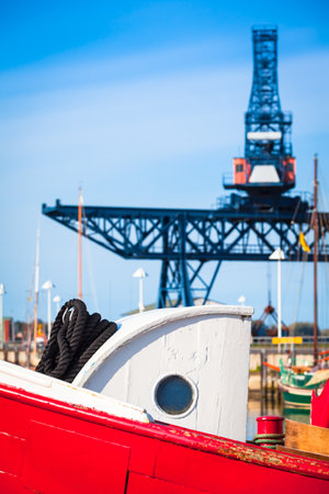 Part of old wooden trawler boat with cabin porthole and crane steel construction at background sky (copy space)の写真素材