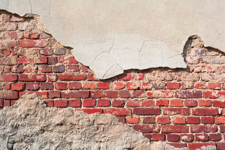Old brick wall background with partly chipped cement plaster (copy space)の写真素材