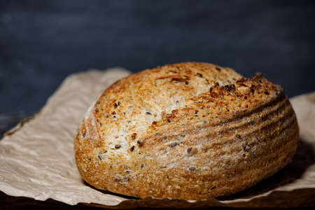 Multi-grain bread with sesame, flax and sunflower seeds on craft paper. Rustic sourdough bread.の写真素材