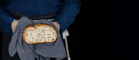 Male hands holding multi-grain rustic bread on a black background