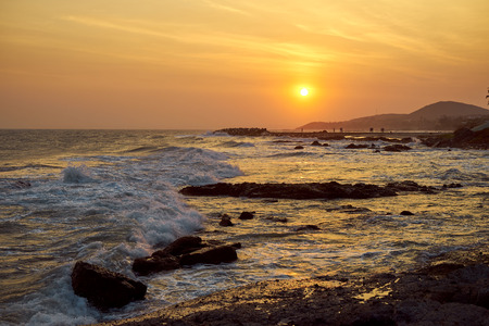 Sunset on the seashore of Vietnam. orange colour of the sky, Hills and people, who meet the evening and looking on wavesの写真素材