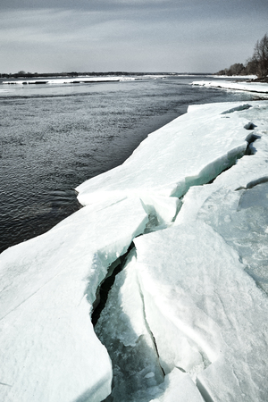 Spring comes in Siberia. Ice crushes on the river, trees stands without leaves in a sunny bright dayの写真素材