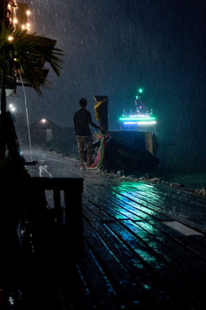 Thai national boat moored to the pier and the guy holds her, meeting guestsの写真素材