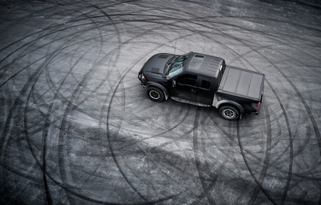 big black matt American pickup truck staying after drifting on the asphalt with tire marksの写真素材