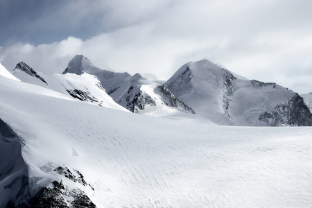 Snow-capped Alpine peaks in Switzerland. Rocks and stones under snow and glaciers in quiet, calm weather. Breithorn summit.の写真素材
