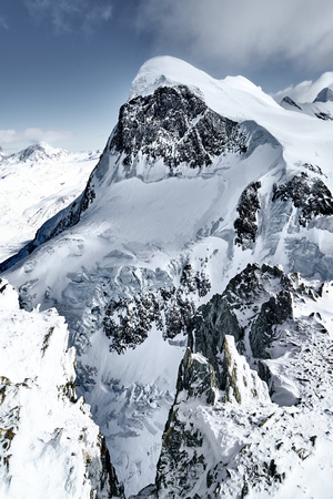 Snow-capped Alpine peaks in Switzerland. Rocks and stones under snow and glaciers in quiet, calm weather. Breithorn summit.の写真素材