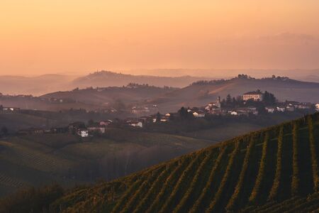 beautiful Italian landscape -evening over Piemonte hills with vineyards with little village on the top of the hillの写真素材