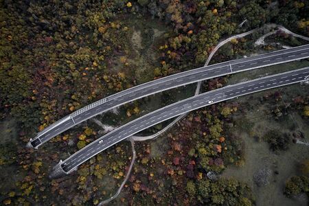 High autumn alpine speed road in Italia with exit or enter into the tunnel. Aerial view from above.の写真素材