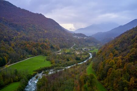 Little Italian village in the valley among the Alps in autumn day with mountains by the sidesの写真素材