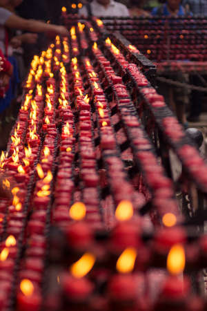 Long rows of many small red candles lit by worshippers at a religious site, central focus with depth of field.の写真素材
